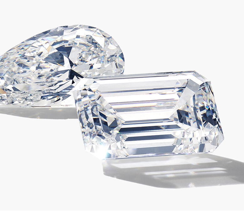 An image of two loose diamonds. One is pear shaped and one is cushion cut.